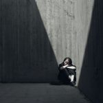 grayscale photo of woman sitting on corner