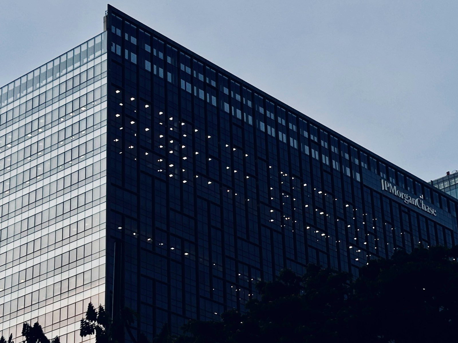 Two modern buildings, one dark with illuminated windows, one reflective.