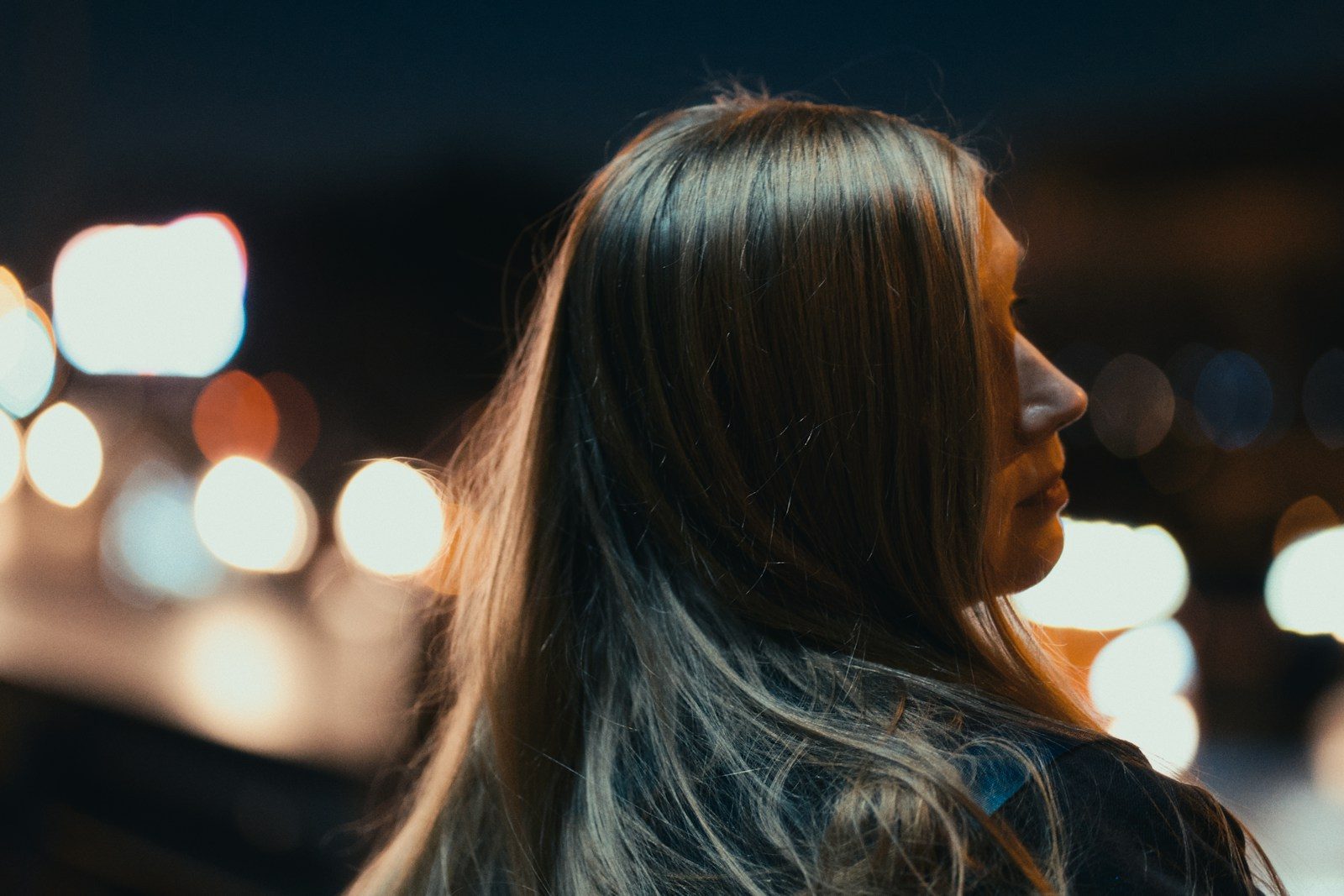 A woman standing in front of a street at night
